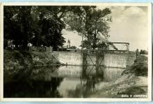 Zdjęcie czarno- białe Śluzy Augustów z 1938 roku, w oddali widać dwie wieże bazyliki w Augustowie.