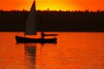 Zdjęcie przedstawia łódź żaglową na jeziorze Necko, w trakcie zachodu słońca fot. J. Koniecko