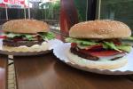 Zdjęcie przedstawia dwa hamburgery na papierowych tackach. 