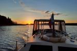 Photo shows white boat and sunset on water.